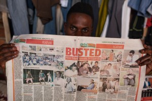 An AJWS grantee in Uganda shields his face with a tabloid article that revealed the names and faces of LGBTI advocates to incite public hatred. Some of them fear violence from homophobic extremists.