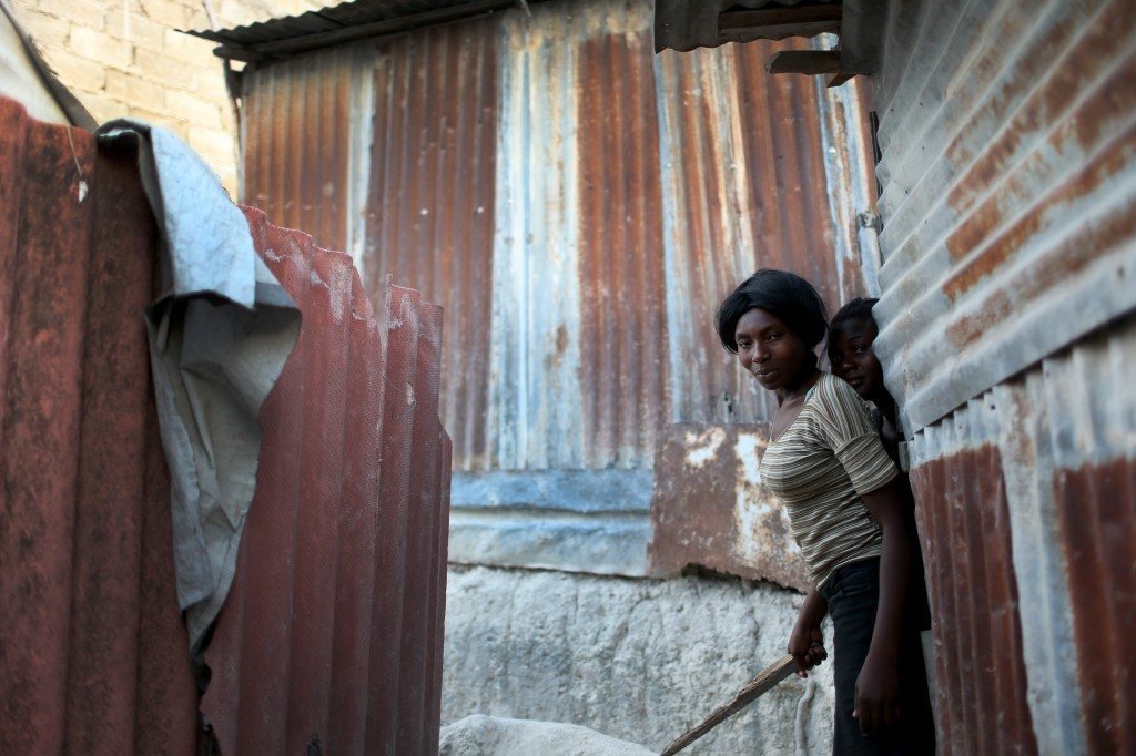 Friends stand together near homes made out of tin and tarps that they built over the land where their homes once stood. Photo by Joe Raedle/Getty Images