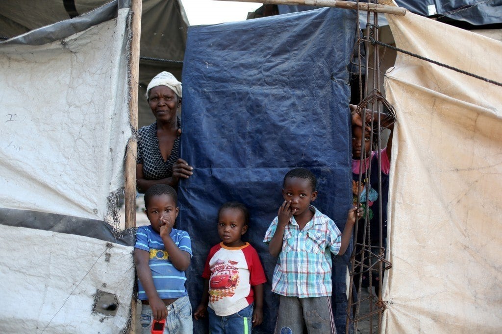 A family looks out from behind the tarp that serves as the front door to their home. Photo by Joe Raedle/Getty Images