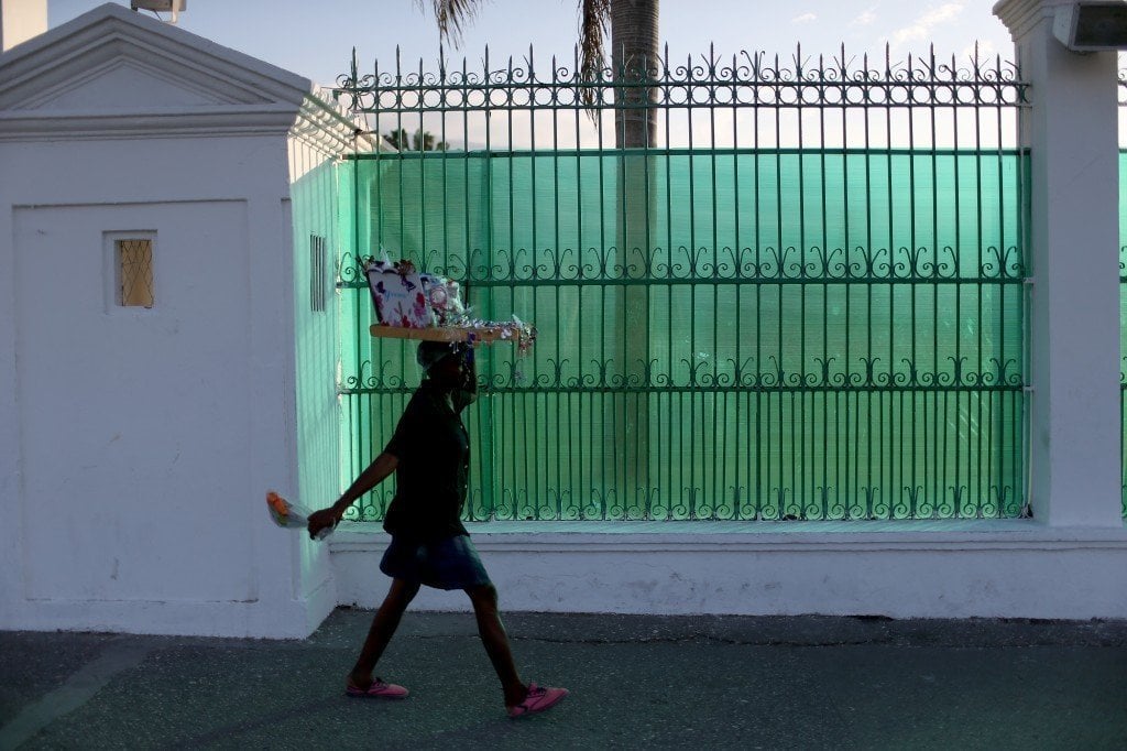 A woman walks past the fence that covers the view of what was the Presidential Palace before it was destroyed when magnitude 7.0 earthquake struck just before 5 p.m. on Jan. 12, 2010 in Port-au-Prince, Haiti. Photo by Joe Raedle/Getty Images