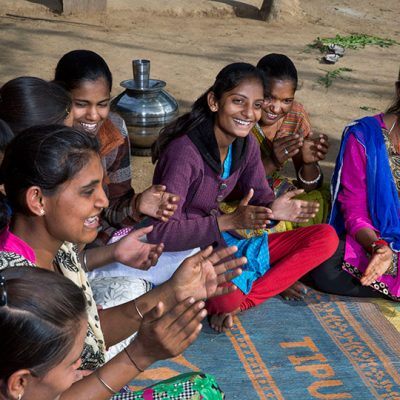 group of young people seated on the ground on a blanket, smiling and looking off camera