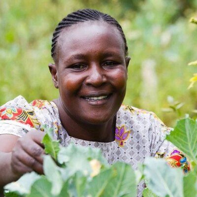 woman harvesting in a green, lush field. the image is close up on her face and hand