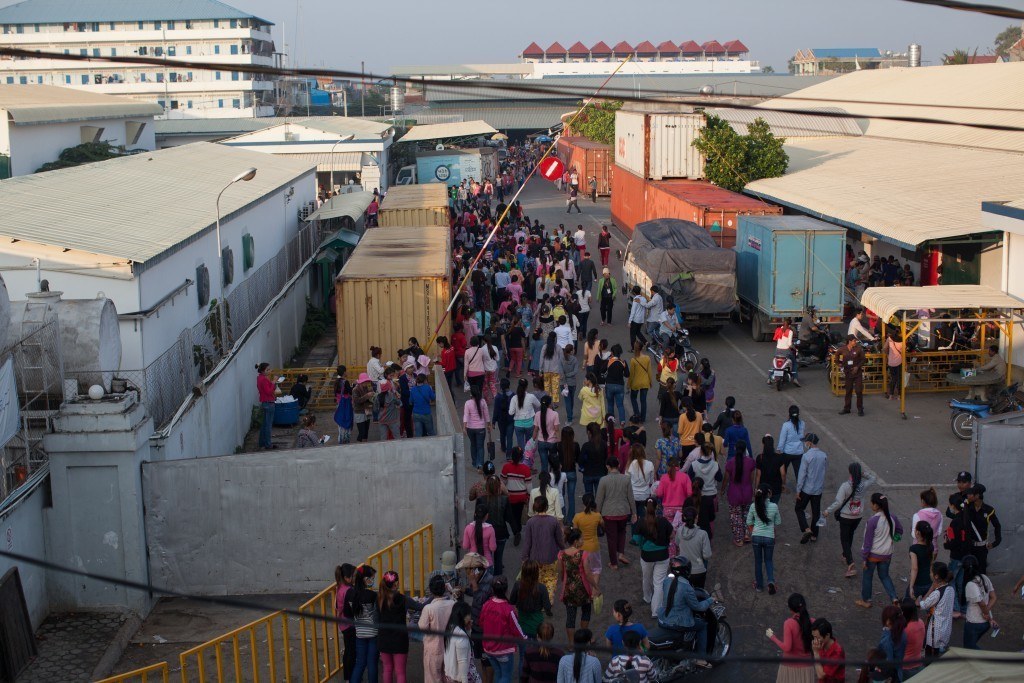 Garment factory workers flood the streets of Phnom Penh's industrial area, en route to work. Here they are seen passing through one garment factory's gates. Photo by Evan Abramson.