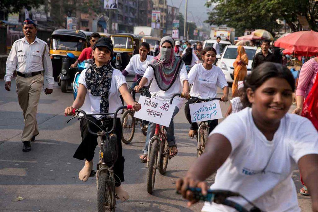 Girls with Awaaz-e-Niswaan ride bikes down a street in Mumbai