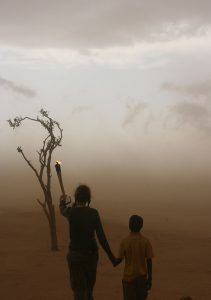 Mia Farrow walking with a child into a dust storm in Chad. Photograph by Ruth W. Messinger