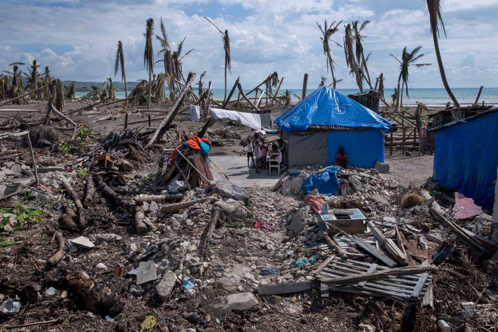 A coastal community in Haiti was damaged by powerful winds- most trees here are destroyed and damaged homes are covered with tarps.