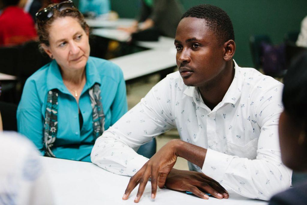 Rabbi Serena Eisenberg (left, wearing a blue top and listening intently) and other AJWS Global Justice Fellows (out of focus, in the background) met Felix Mornau (right, wearing a white shirt, gesturing with one hand and speaking), a 19-year-old baseball player whose chance at playing for the San Diego Padres in 2015 was thwarted by the 2013 court ruling, which made it impossible for him to obtain the legal ID required for his contract. Felix has received help from Reconoci.do. “They gave me hope,” he said. “I never thought I would have hope.” Photograph by Christine Han 