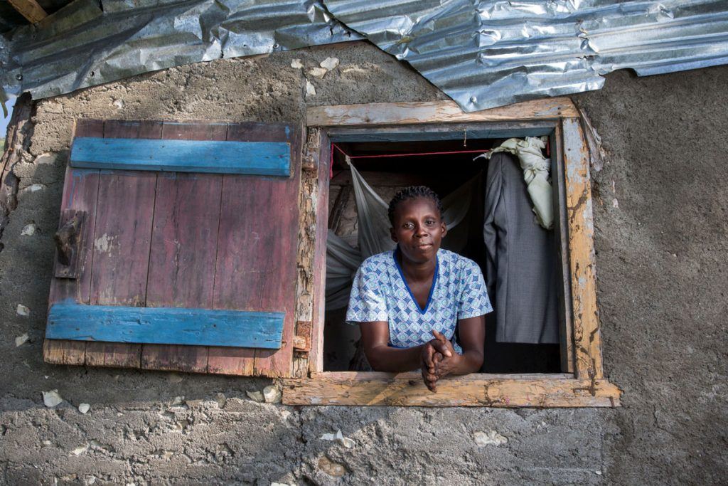 Tèt Kole member Marie Yolene Dossous, leaning out the window of a home with a tin roof, is helping Haiti’s rural poor get back on their feet. Photo by Jonathan Torgovnik 