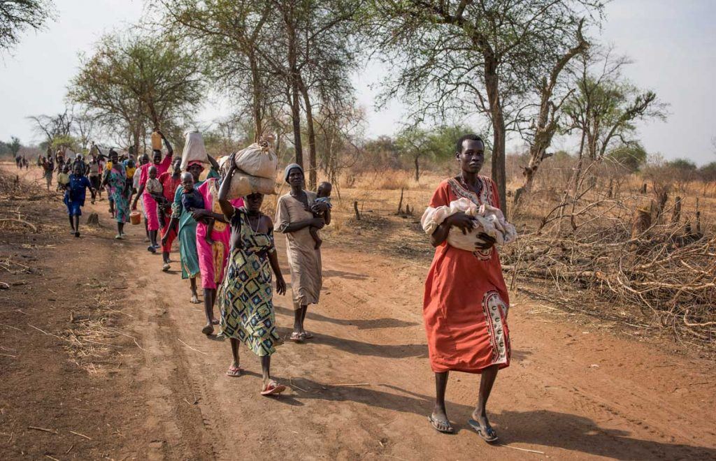 In this photo taken Wednesday, April 5, 2017, people walk for hours to reach a food distribution site in Malualkuel, in the Northern Bahr el Ghazal region of South Sudan. Two months after a famine was declared in two counties amid its civil war, hunger has become more widespread than expected, aid workers say, with the Northern Bahr el Ghazal region on the brink of starvation and 290,000 people at risk of dying without sustained food assistance. (AP Photo)