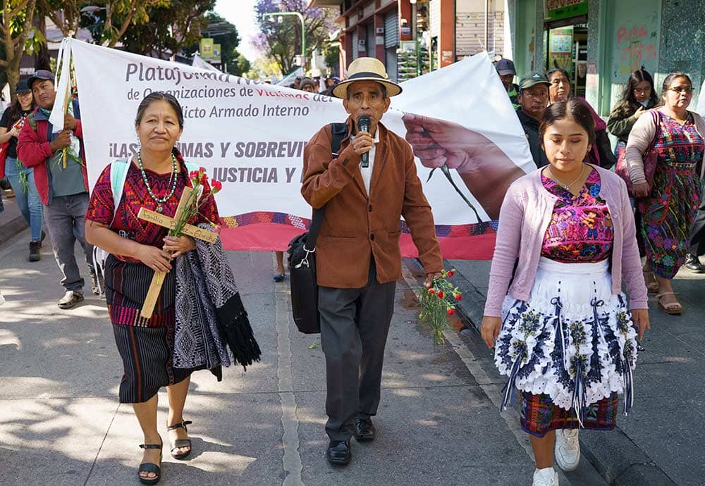 protestors holding crosses and banners, the one in the middle speaking into a microphone