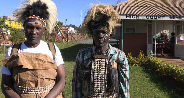 two people outside looking at camera, wearing indigenous attire