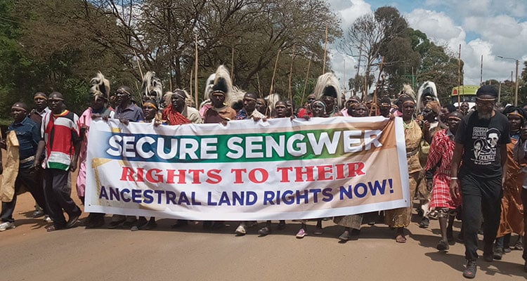group of indigenous people marching with a banner that says Secure Sengwer rights to their ancestral land rights now!