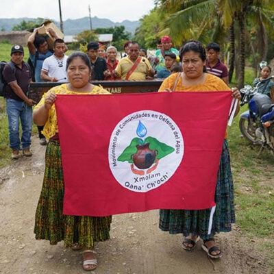 group of people outside holding up a red banner
