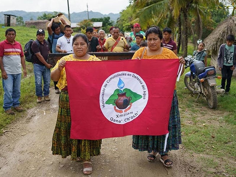 group of people outside holding up a red banner