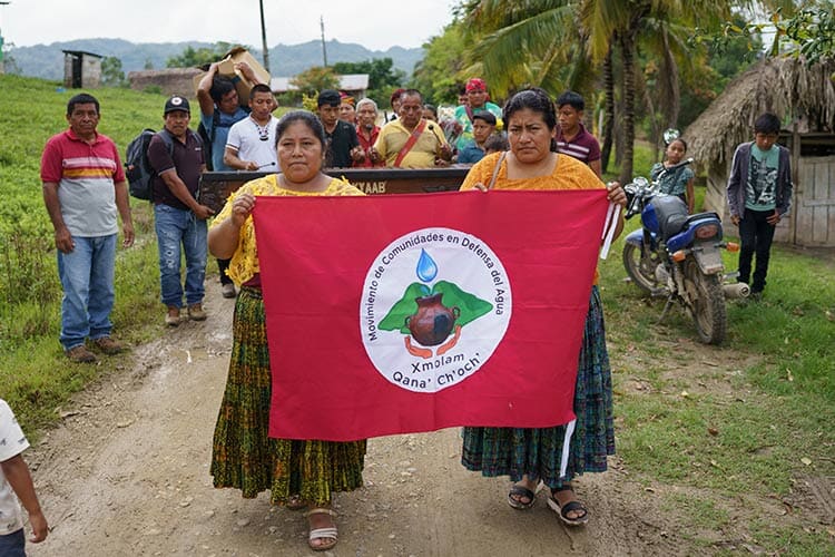 group of people outside holding up a red banner