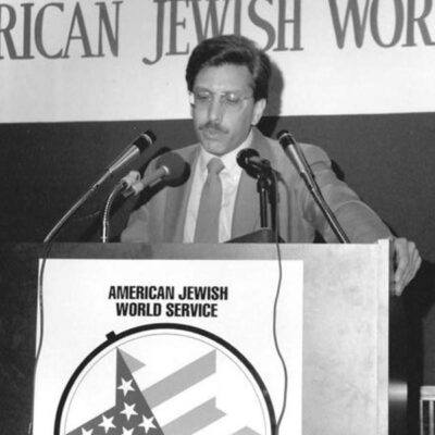 Larry Simon speaking at podium in black and white