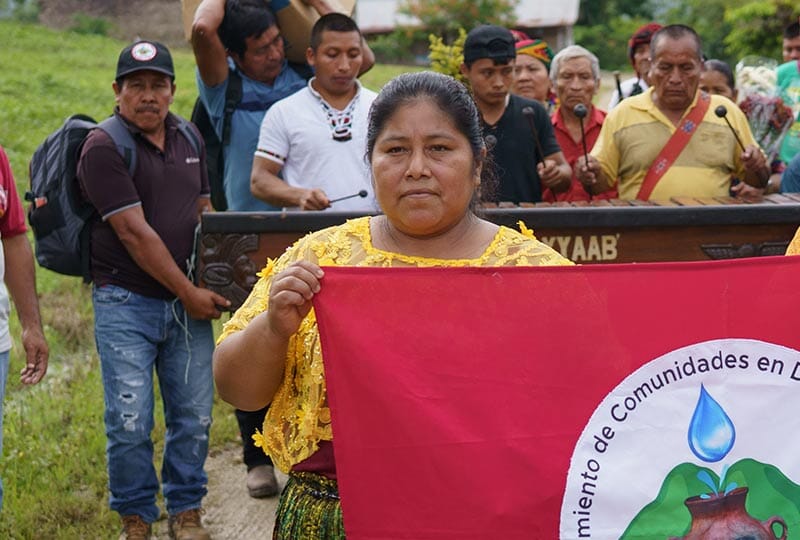 group of people outside holding up a red banner
