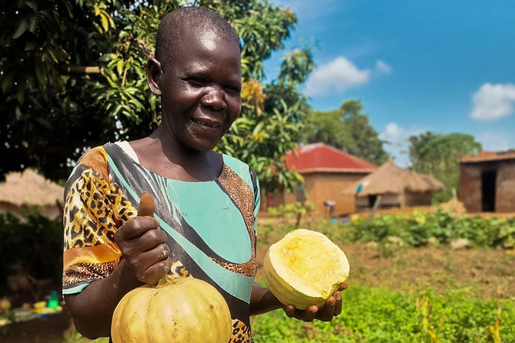 woman outside smiling and holding a fruit