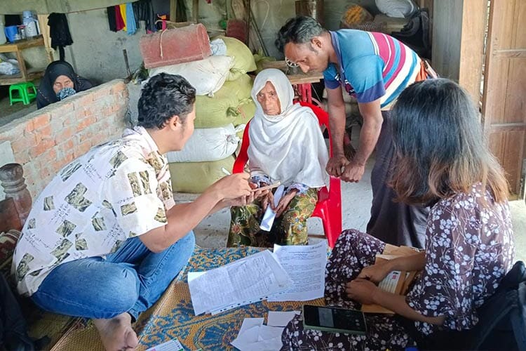 three PDI staff assist an elderly woman seated in a red chair