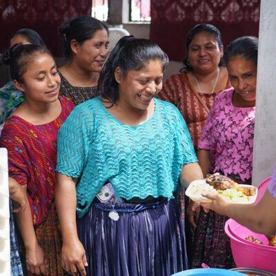 group of women smiling over a plate of food