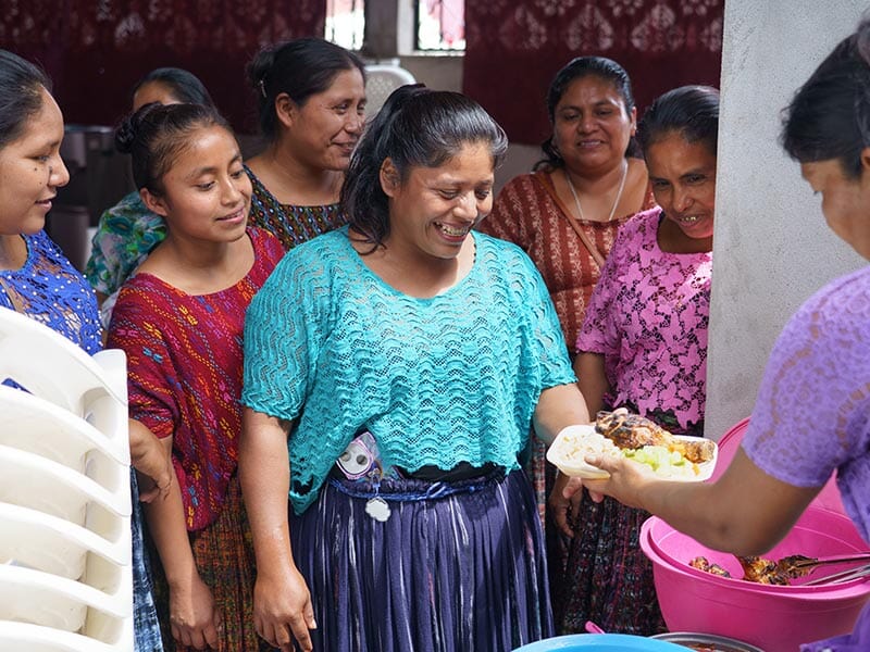 group of women smiling over a plate of food