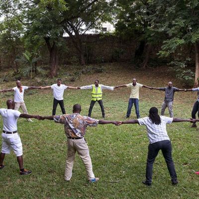 people holding hands around a circle on the grass
