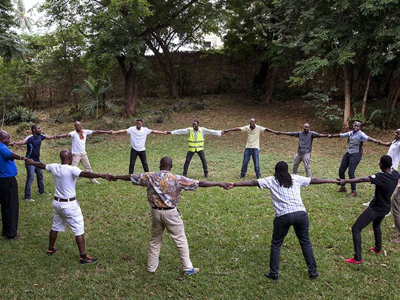 people holding hands around a circle on the grass