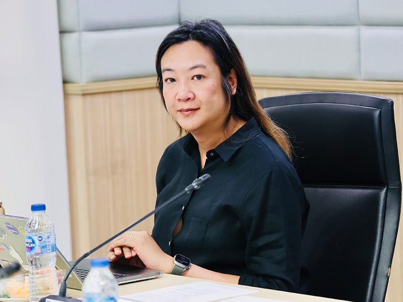 Hua looking at camera while seated at a desk