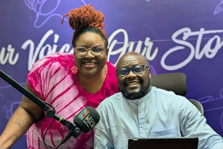 two people smiling at the camera behind a mic