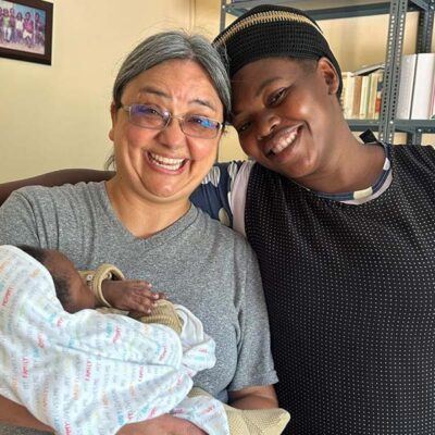 two women smiling with a new baby
