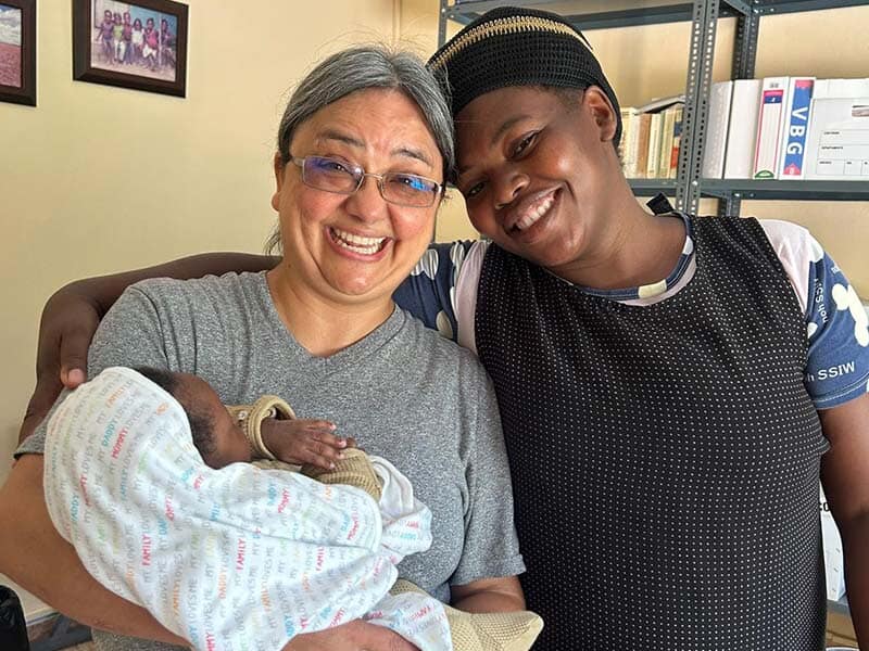 two women smiling with a new baby