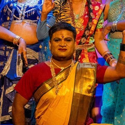 performer striking a pose wearing a red tshirt and gold sari