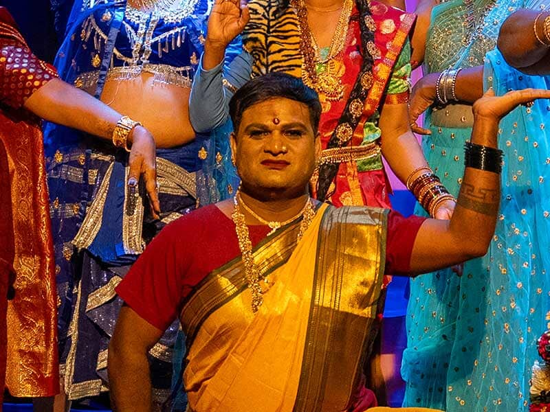 performer striking a pose wearing a red tshirt and gold sari