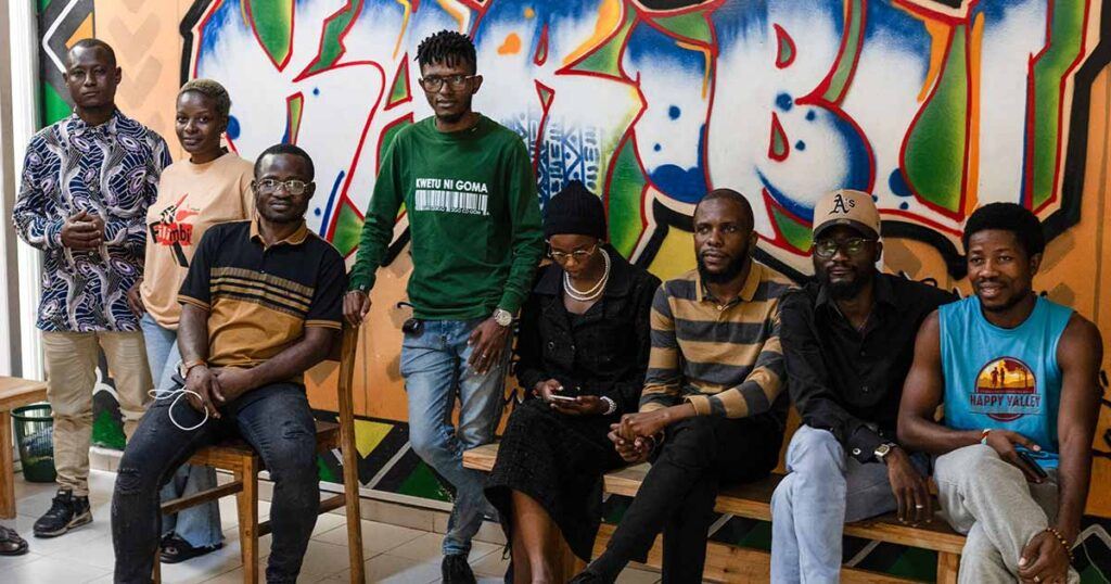group of people sitting on benches in front of a muraled wall
